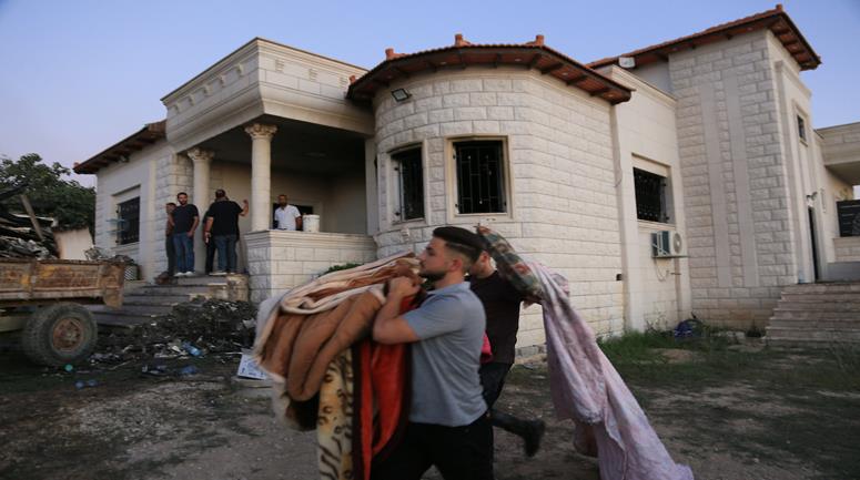 مواطنون يتفقدون المنزل الذي أحرقه المستعمرون في قرية تل غرب مدينة نابلس